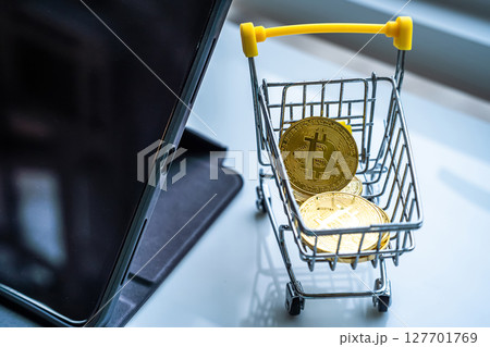 Close-up of Golden bitcoins or cryptocurrency coin or symbols in shopping cart and tablet in white table. Future currency concept. Close-up of Golden bitcoins or cryptocurrency coin or symbols in shopping cart and tablet in white table. Future currency concept. 127701769