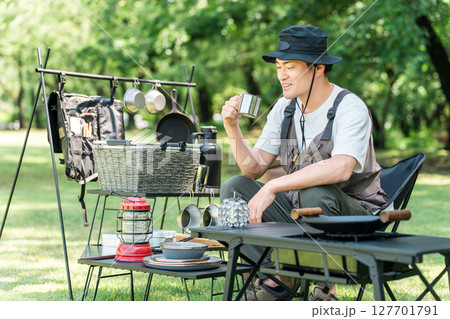 キャンプ場の芝生のサイトでソロキャンプする中年男性キャンパー 127701791
