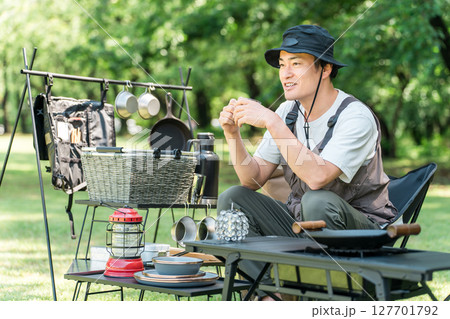 キャンプ場の芝生のサイトでソロキャンプする中年男性キャンパー 127701792