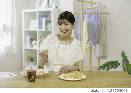 リビングでカップ麺を食べようとする若い女性 127703068