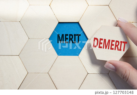 Merit or Demerit symbol. Concept word Merit or Demerit on wooden comb puzzle. Businessman hand. Beautiful blue background. Business and Merit or Demerit concept. Copy space 127703148