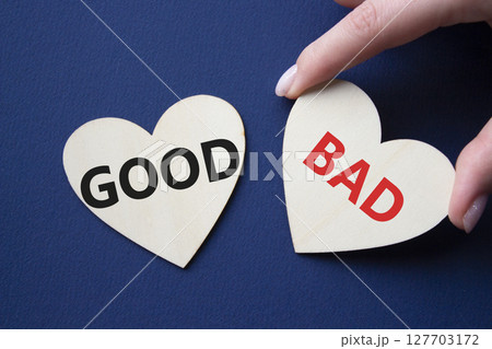 Good or Bad symbol. Concept word Good or Bad on wooden hearts. Businessman hand. Beautiful deep blue background. Business and Good or Bad concept. Copy space 127703172