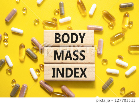 Body Mass Index symbol. Concept word Body Mass Index on wooden blocks. Beautiful yellow background with pills. Medicine and Body Mass Index concept. Copy space 127703513