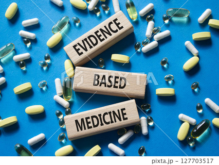 Evidence Based Medicine symbol. Concept word Evidence Based Medicine on wooden blocks. Beautiful blue background with pills. Medicine and Evidence Based Medicine concept. Copy space 127703517