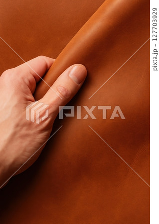 Hand touching smooth brown leather surface 127703929