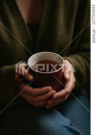 Cozy hands holding a warm cup of tea 127703933