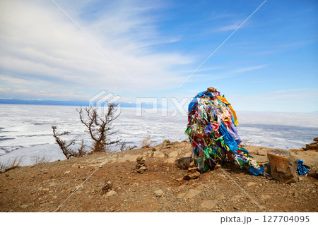 A pillar with multicolored ribbons for making wishes. A popular tourist destination in the north of Olkhon Island A pillar with multicolored ribbons for making wishes. A popular tourist destination in the north of Olkhon Island 127704095