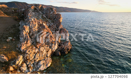 Lake Baikal at sunset. A rock with a hole in the shape of a heart on Cape Tsagan-Khushun Lake Baikal at sunset. A rock with a hole in the shape of a heart on Cape Tsagan-Khushun 127704098