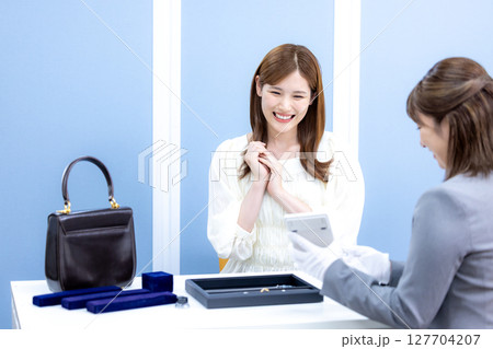 買取業者　バックと貴金属の査定をしてもらっている女性 127704207