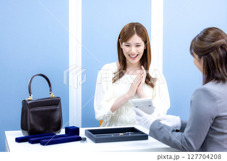 買取業者 バックと貴金属の査定をしてもらっている女性 買取業者 バックと貴金属の査定をしてもらっている女性 127704208