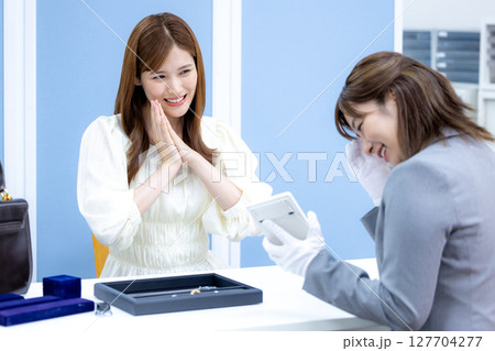 買取業者 バックと貴金属の査定をしてもらっている女性 買取業者 バックと貴金属の査定をしてもらっている女性 127704277