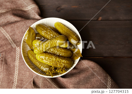 Marinated cucumbers in a bowl on a dark wooden background. Homemade pickles. Marinated cucumbers in a bowl on a dark wooden background. Homemade pickles. 127704315