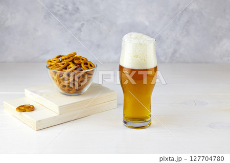 A glass of light beer with pretzels on a white wooden background A glass of light beer with pretzels on a white wooden background 127704780