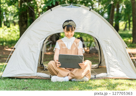 キャンプ場・レジャー施設でテントでタブレットを使う女の子 127705363