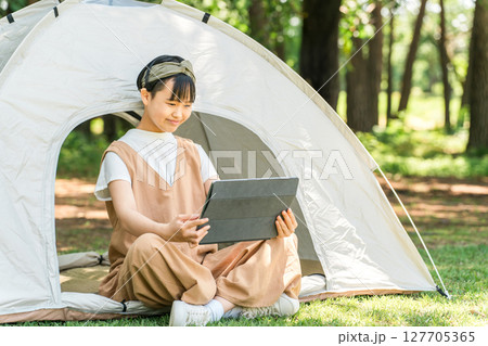 キャンプ場・レジャー施設でテントでタブレットを使う女の子 127705365