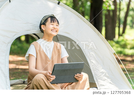 キャンプ場・レジャー施設でテントでタブレットを使う女の子 127705368