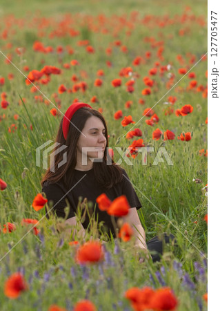Young Woman in Poppy Field with Red Hat 127705477