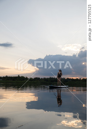 Paddleboarding at Sunset on a Tranquil Lake 127705525