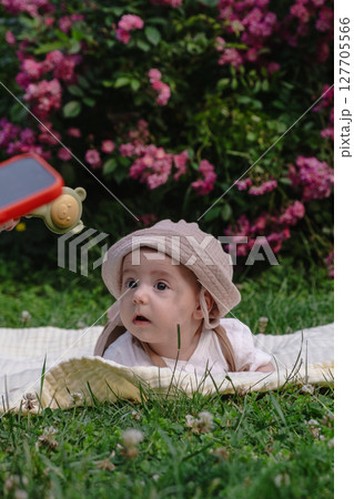 Child Lying on Blanket Surrounded by Pink Flowers 127705566