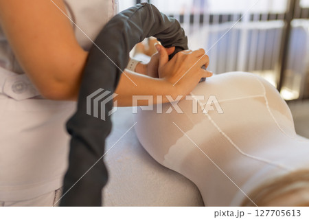 Woman in special white suit getting anti cellulite massage in a spa salon. LPG, and body contouring treatment in clinic.Reset body weight with LPG massage. Woman in special white suit getting anti cellulite massage in a spa salon. LPG, and body contouring treatment in clinic.Reset body weight with LPG massage. 127705613