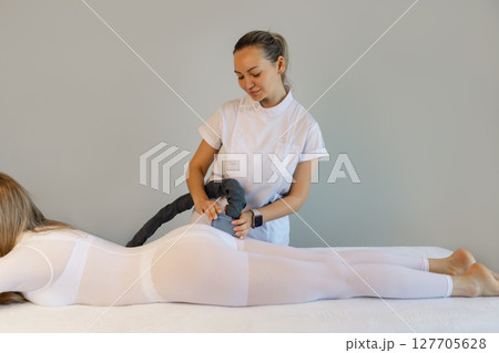 Woman in special white suit getting anti cellulite massage in a spa salon. LPG, and body contouring treatment in clinic.Reset body weight with LPG massage.  127705628