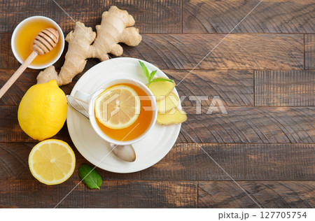 Herbal tea with lemon and ginger on wooden table, accompanied by honey and fresh ingredients, showcasing a healthy beverage concept Herbal tea with lemon and ginger on wooden table, accompanied by honey and fresh ingredients, showcasing a healthy beverage concept 127705754