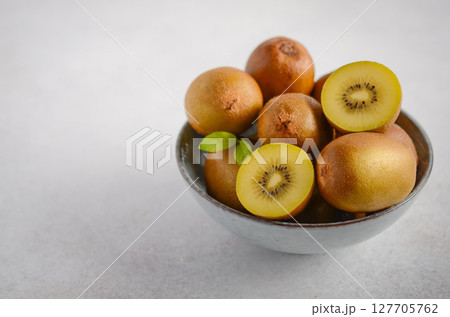 Fresh golden kiwifruit arranged in a rustic bowl, showcasing vibrant colors and textures, perfect for healthy eating and culinary inspiration 127705762