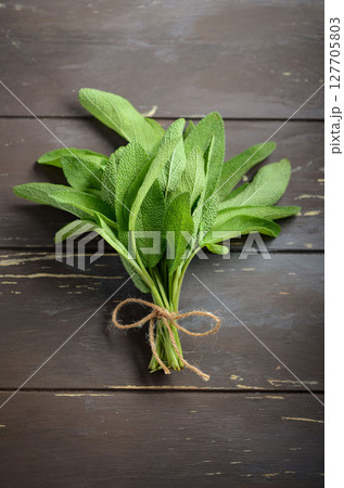 Freshly harvested sage bundle tied with twine, resting on rustic wooden surface, showcasing vibrant green leaves and natural textures Freshly harvested sage bundle tied with twine, resting on rustic wooden surface, showcasing vibrant green leaves and natural textures 127705803