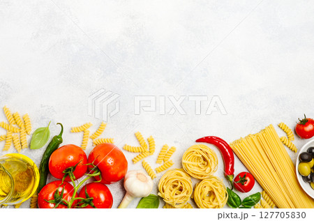 Fresh ingredients for Italian cuisine arranged on a light background, featuring pasta, tomatoes, garlic, and herbs for culinary inspiration 127705830