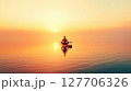 Serene meditation at sunset on tranquil water with warm hues illuminating the horizon and creating a peaceful atmosphere 127706326