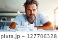 Architect focuses on building model while working in modern office, showcasing creativity and design skills during a bright morning in an urban setting 127706328