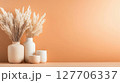Neutral home decor featuring dried flowers in vases and candles against a soft orange backdrop for a warm ambiance in interior design 127706337