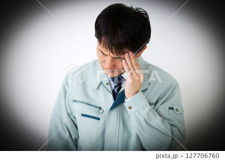 グリーンの作業服を着て悩むミドル男性ビジネスマン 127706760