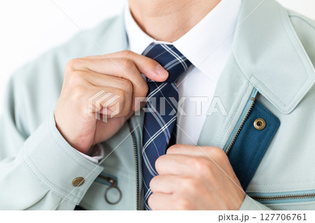 グリーンの作業服を着てネクタイを結ぶミドル男性ビジネスマン 127706761
