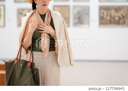 Close up of young Caucasian woman looks at an exhibition of paintings in a modern gallery in bewilderment and embarrassment. Concept of museum day Close up of young Caucasian woman looks at an exhibition of paintings in a modern gallery in bewilderment and embarrassment. Concept of museum day 127706941