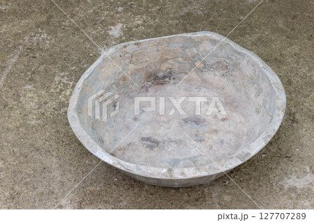 Weathered dented gray aluminum basin on concrete floor 127707289