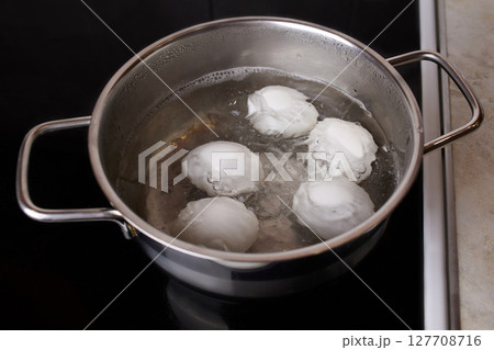 A saucepan with boiled chicken eggs on an electric stove 127708716