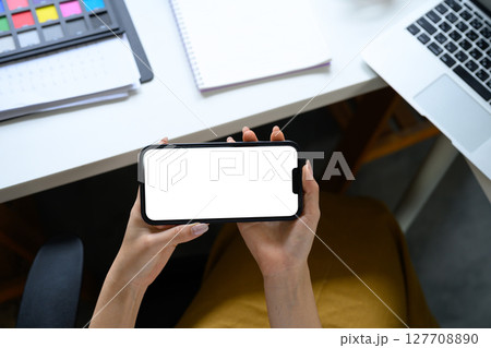 Woman using a smartphone in landscape mode in creative studio Woman using a smartphone in landscape mode in creative studio 127708890