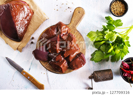 Raw Beef liver meat on wooden board with peppers Raw Beef liver meat on wooden board with peppers 127709316