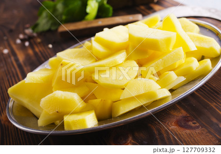 Spiced pieces of raw potato prepared to bake. 127709332