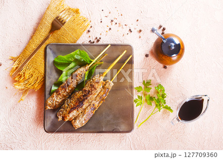 Grilled Lula kebab on skewers with spices in a claim plate on a table 127709360
