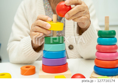 Asian elderly woman playing enhancing skill board game. 127710174