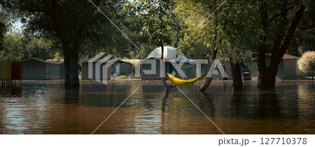 A hammock is strung between trees in a flooded area, creating an unusual yet serene scene. 127710378