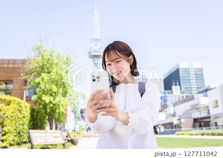 屋外でスマホを操作する若い女性 屋外でスマホを操作する若い女性 127711042