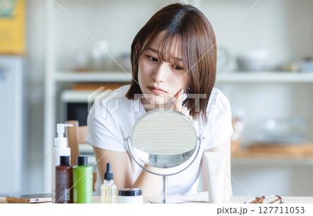 鏡を見てお肌のチェックをする女性 鏡を見てお肌のチェックをする女性 127711053