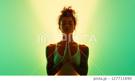 Meditation practice with a serene woman surrounded by soft glowing light in a tranquil setting during evening hours for relaxation and mindfulness 127711690