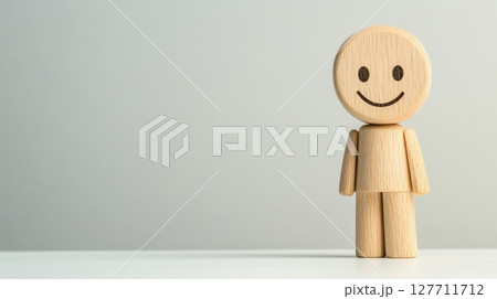 Wooden figure with a smile stands on a clean white surface, conveying positivity and warmth in a minimalistic indoor setting 127711712