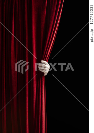 Red velvet curtain pulled aside by hand, revealing black emptiness. Theater posters, film teasers. 127713035