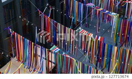 Aerial view of colorful ribbons hanging from the ceiling in an office building, symbolizing diversity and creativity Aerial view of colorful ribbons hanging from the ceiling in an office building, symbolizing diversity and creativity 127713674