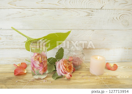 Spa still life with pink fresh roses flowers, candle and rose petal water, on wooden background. Alternative medicine, aromatherapy, body care. Spa still life with pink fresh roses flowers, candle and rose petal water, on wooden background. Alternative medicine, aromatherapy, body care. 127713954